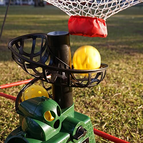 Automatic ball launcher with basketball net in a grassy field.