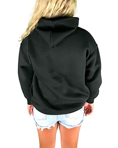 Person wearing a black hoodie and denim shorts, viewed from the back.