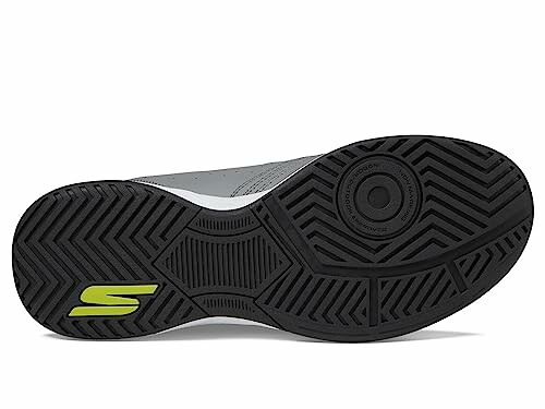 Bottom view of a black sneaker sole with a green logo.