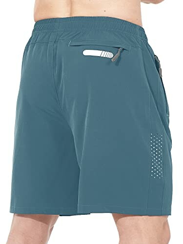 Back view of a man wearing blue athletic shorts with a zipper pocket.