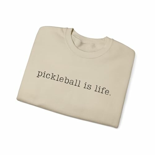 Folded beige t-shirt with 'pickleball is life' printed on it.