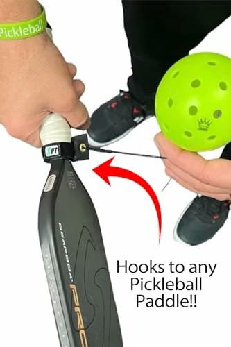 Person attaching a pickleball to a paddle with a strap.