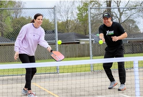 Two people playing pickleball on an outdoor court.