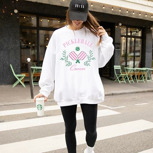 Person wearing 'Pickleball Queen' sweatshirt holding coffee