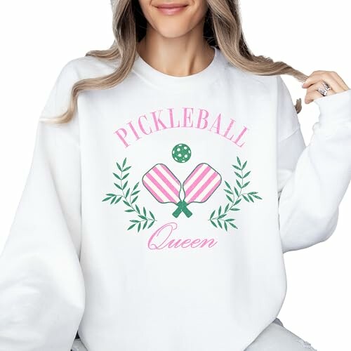 Woman wearing a white sweatshirt with 'Pickleball Queen' design.