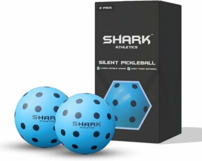 Two blue pickleball balls with black dots and Shark Athletics branding next to a box.