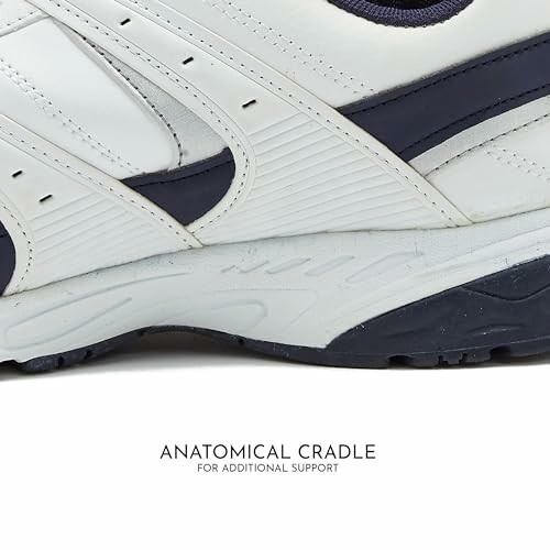 Closeup of a white sneaker with navy details, featuring anatomical cradle support.