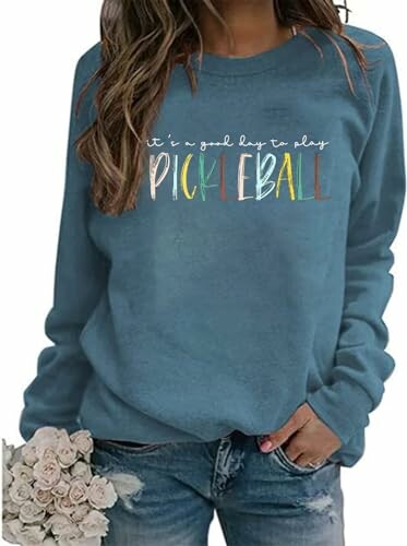 Woman in blue sweatshirt with pickleball text holding flowers