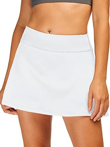 Woman wearing a white athletic skirt and sports bra.